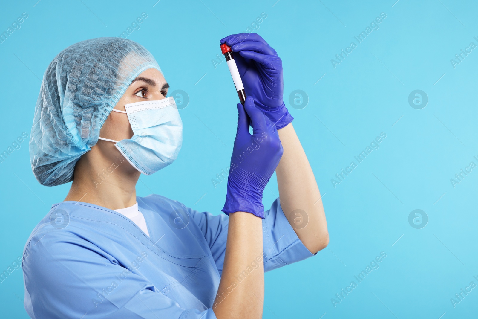 Photo of Laboratory testing. Doctor with blood sample in tube on light blue background, space for text