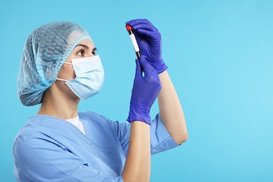 Photo of Laboratory testing. Doctor with blood sample in tube on light blue background, space for text