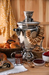 Photo of Traditional Russian samovar and treats on wooden table