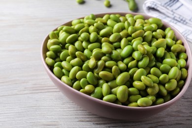 Photo of Bowl of delicious edamame beans on light wooden table, closeup