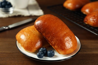 Photo of Delicious baked pirozhki with blueberries on wooden table, closeup