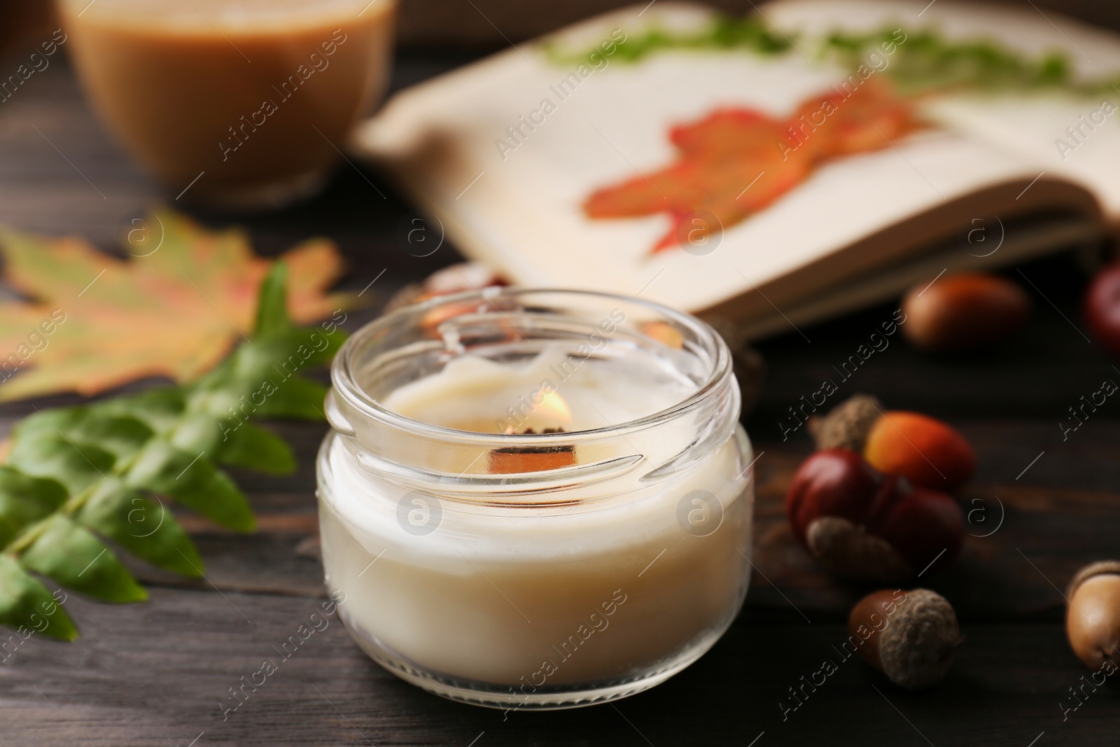 Photo of Composition with scented candle and autumn leaves on wooden table