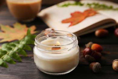 Photo of Composition with scented candle and autumn leaves on wooden table