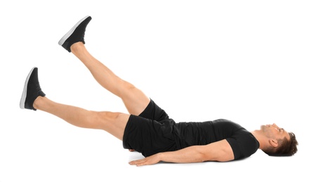 Young man doing scissors exercise on white background