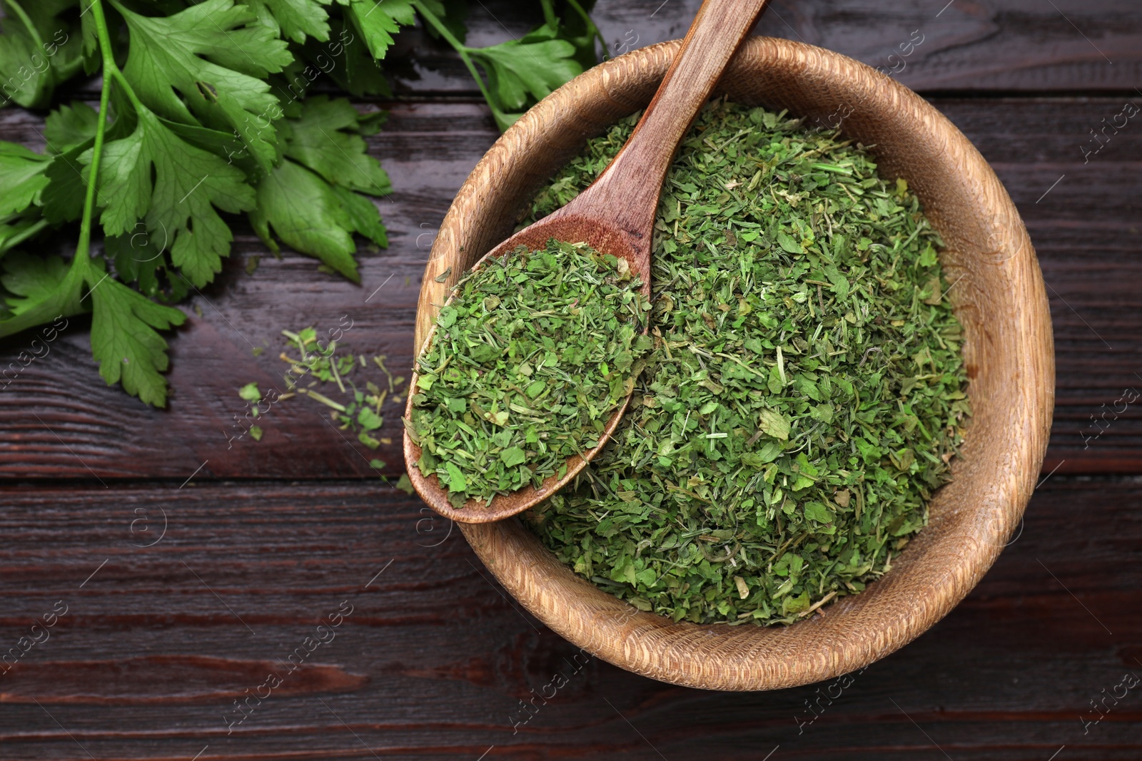 Photo of Dried aromatic parsley and fresh leaves on wooden table, flat lay. Space for text