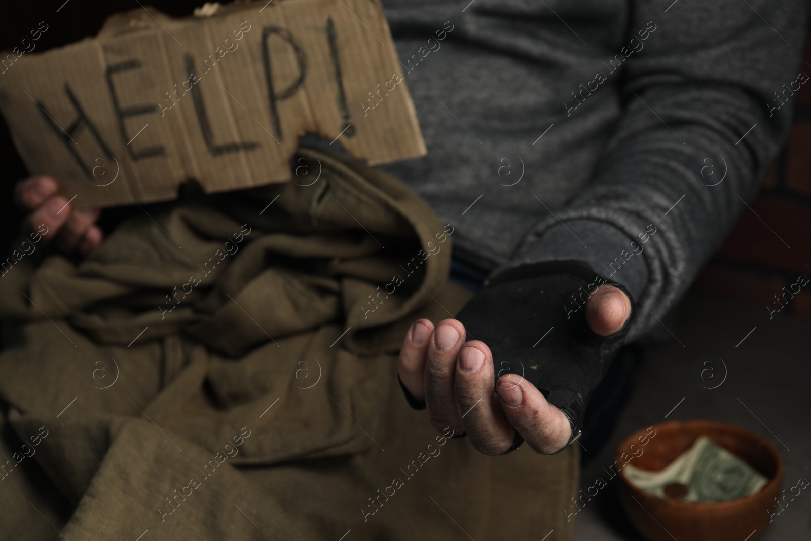 Photo of Poor homeless man with help sign begging for money, closeup. Charity and donation