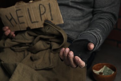 Photo of Poor homeless man with help sign begging for money, closeup. Charity and donation