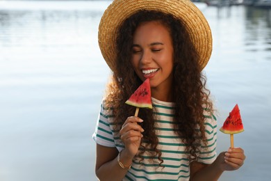 Photo of Beautiful young African American woman with pieces of watermelon near river