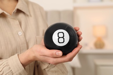 Woman holding magic eight ball indoors, closeup