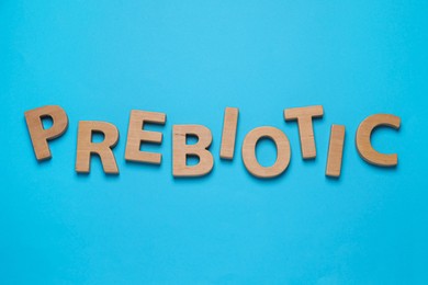 Photo of Word Prebiotic made of wooden letters on light blue background, flat lay