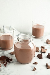 Glassware with tasty chocolate milk on marble table. Dairy drink