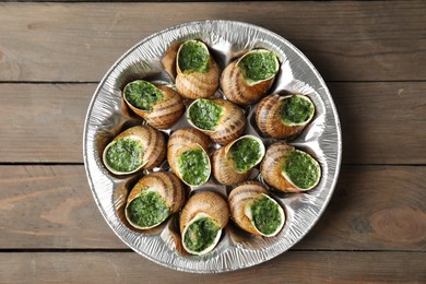 Photo of Delicious cooked snails on wooden table, top view