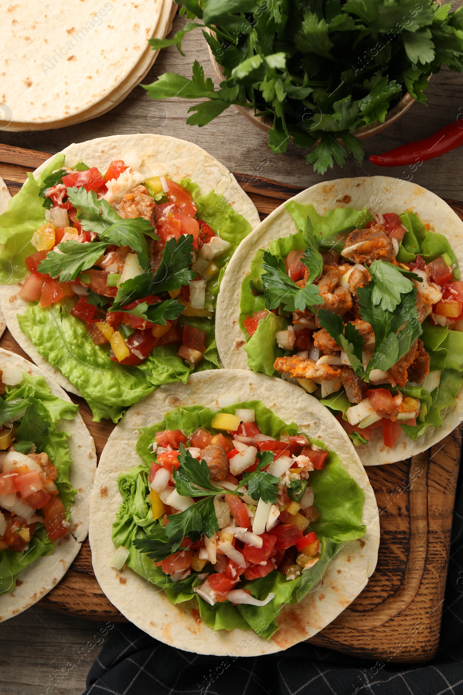 Photo of Delicious tacos with vegetables and meat on wooden table, flat lay