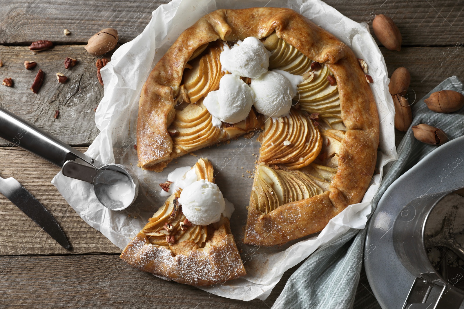 Photo of Delicious apple galette served with ice cream on wooden table, flat lay