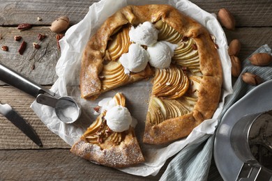 Delicious apple galette served with ice cream on wooden table, flat lay