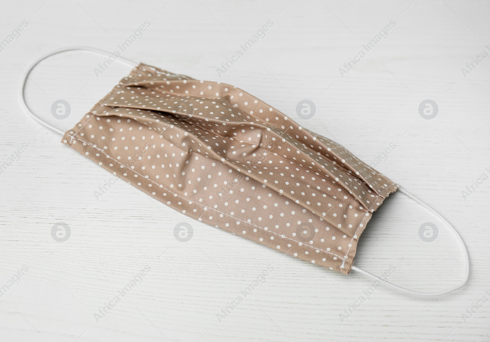 Photo of Handmade cloth mask on white wooden background. Personal protective equipment during COVID-19 pandemic