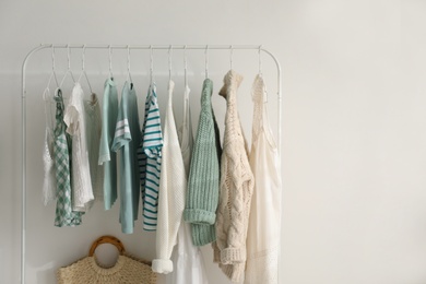 Photo of Rack with stylish women's clothes near white wall, space for text. Interior design