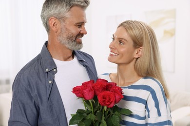 Happy affectionate couple with bouquet of roses at home. Romantic date