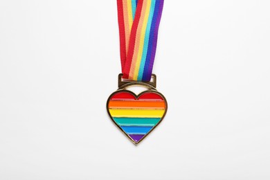 Rainbow ribbon with heart pendant on white background, top view. LGBT pride