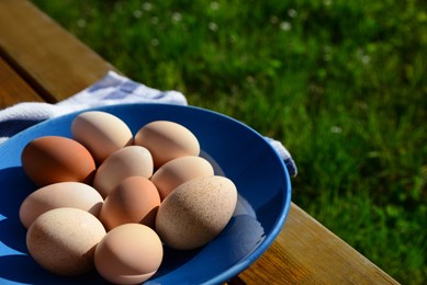 Photo of Plate of assorted eggs and napkin on wooden table outdoors. Space for text