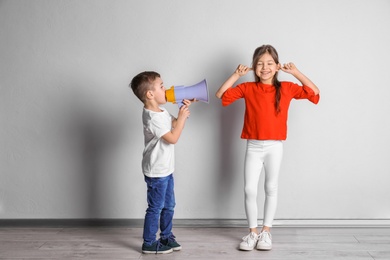 Photo of Adorable little kids with megaphone near light wall