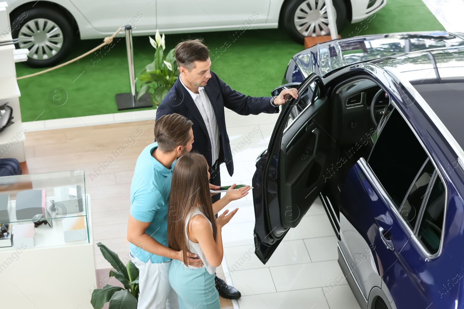 Photo of Salesman consulting young couple in car salon