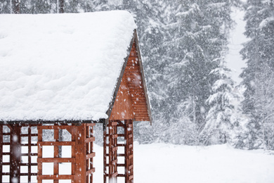 Photo of Modern wooden gazebo on snowy day. Winter vacation