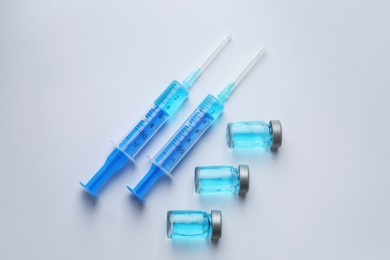 Disposable syringes with needles and vials on white background, top view