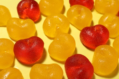 Photo of Delicious gummy cherry candies on yellow background, closeup