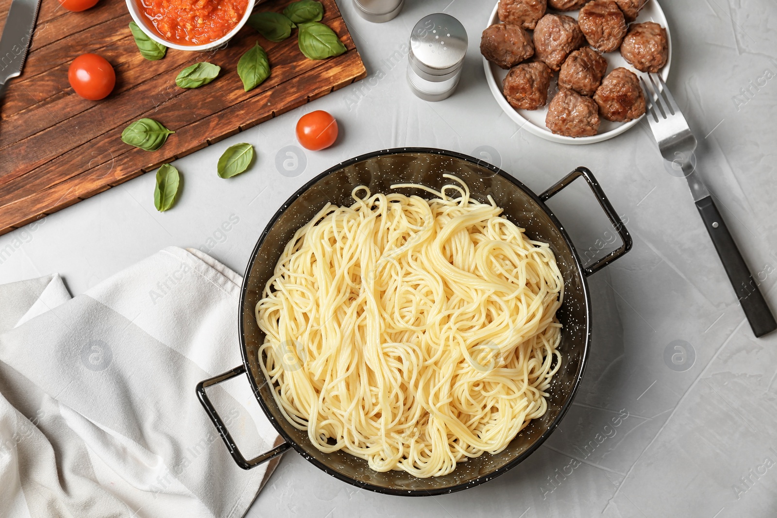 Photo of Frying pan with pasta, meatballs and sauce on grey background