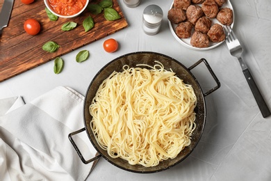 Photo of Frying pan with pasta, meatballs and sauce on grey background