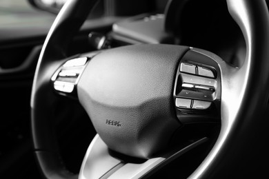 Black steering wheel inside of modern car, closeup