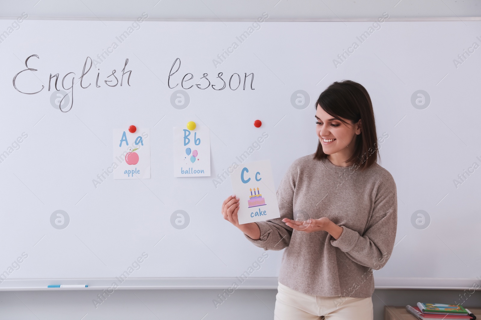 Photo of Happy female English teacher giving lesson indoors. Early childhood education