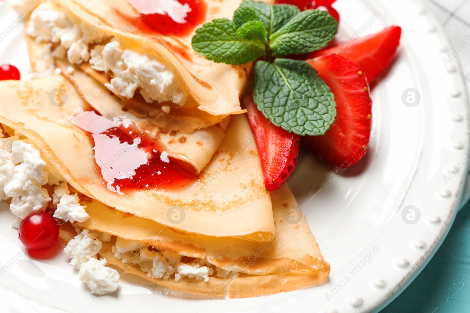 Photo of Delicious thin pancakes with cottage cheese and jam on plate, closeup