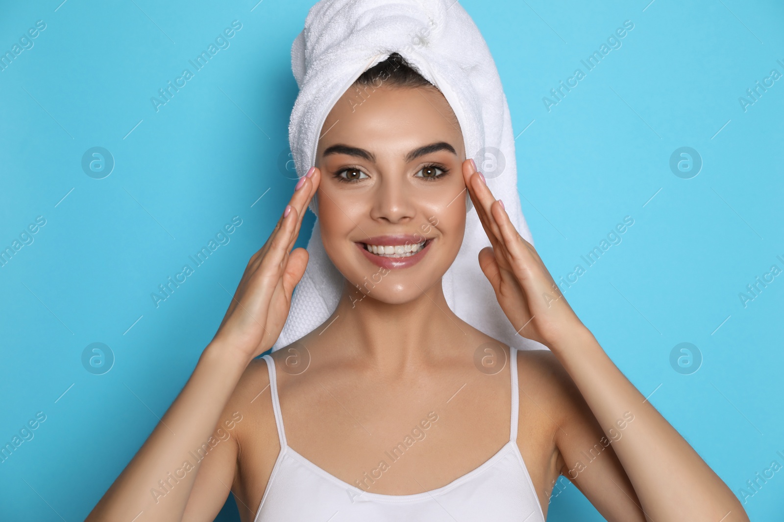 Photo of Beautiful young woman with towel on head against light blue background