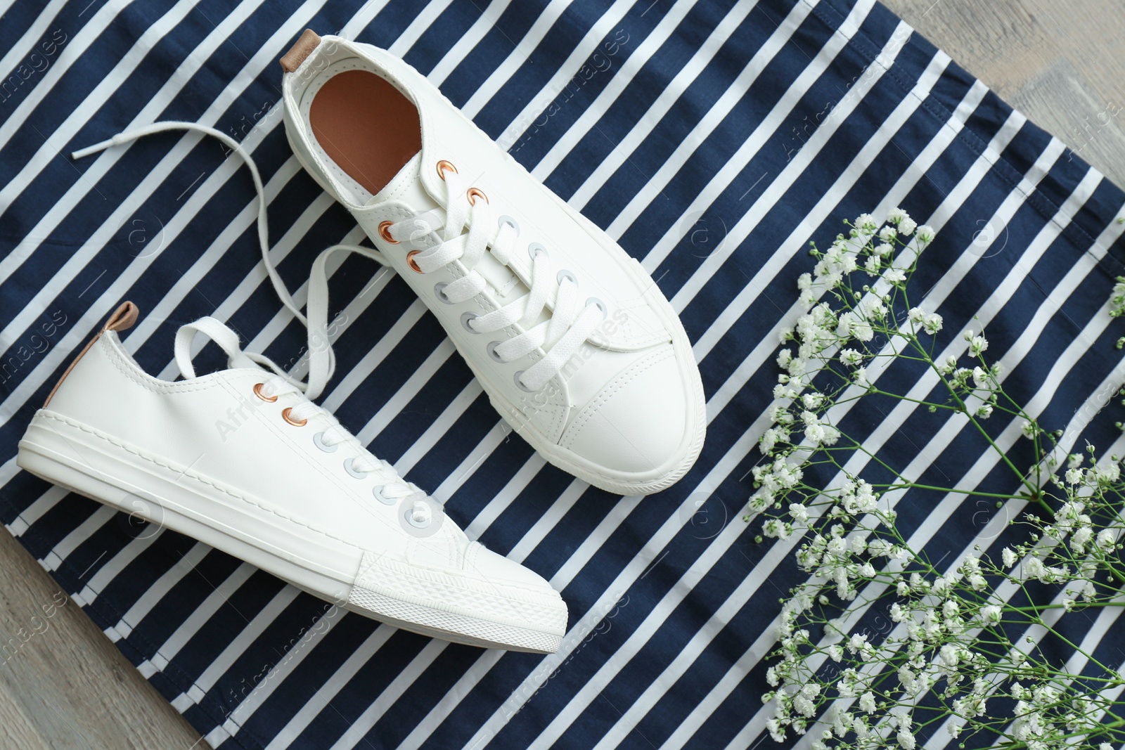 Photo of Comfortable casual female shoes and flowers on striped fabric