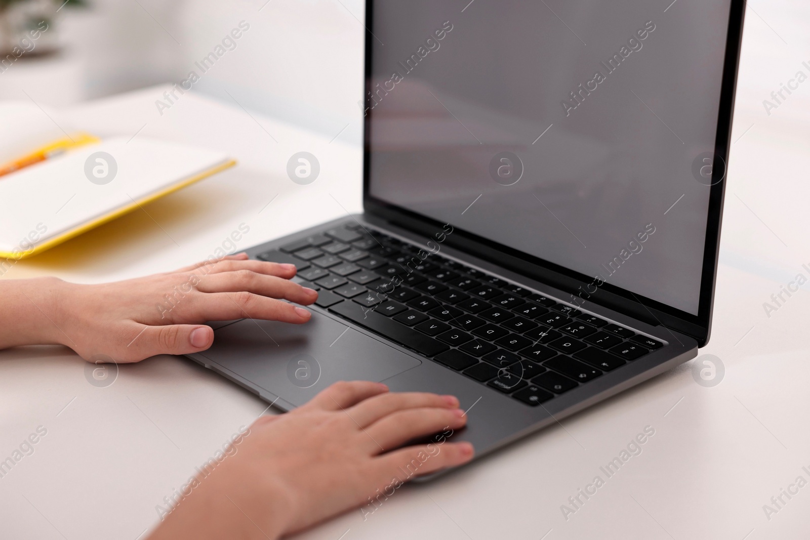 Photo of E-learning. Girl using laptop during online lesson at table indoors, closeup