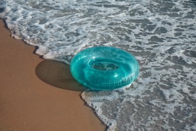 Bright inflatable ring on sandy beach near sea