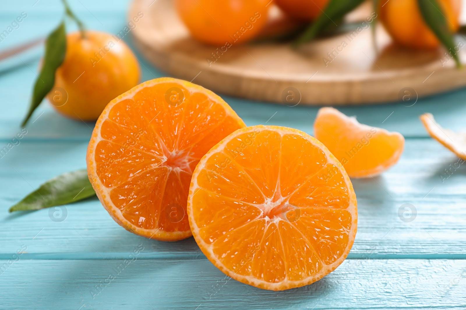 Photo of Cut fresh ripe tangerines on light blue table