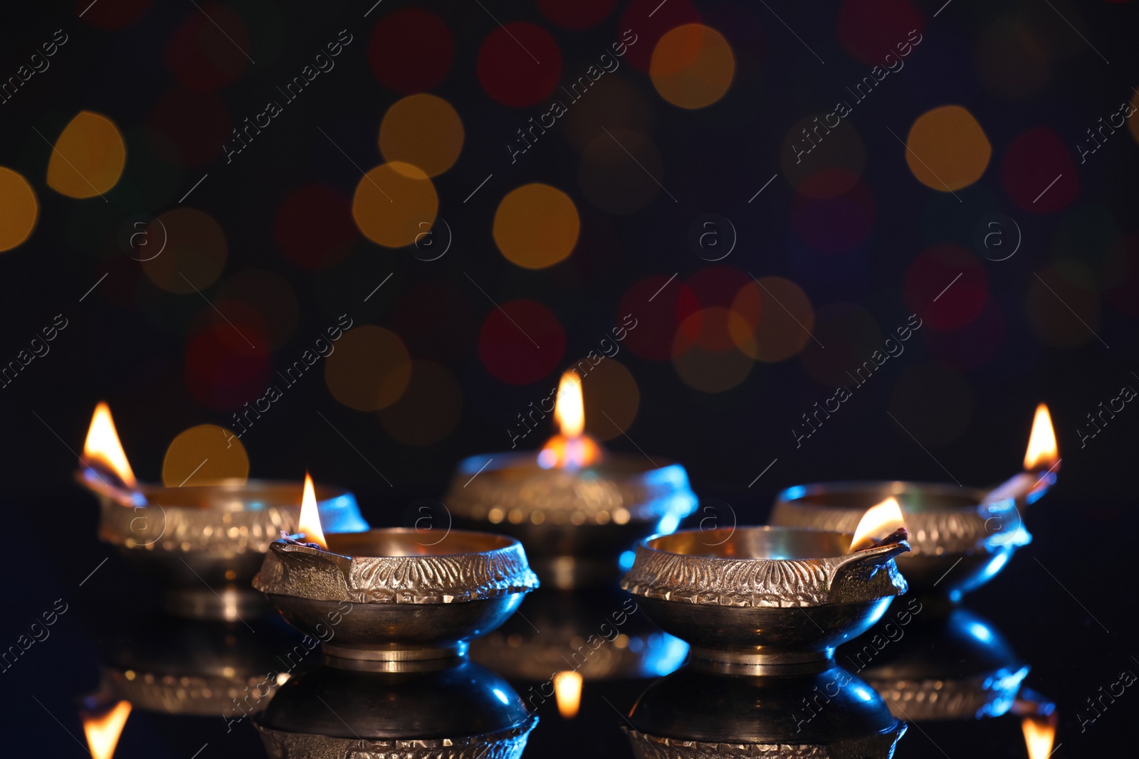 Photo of Many lit diyas on dark background with blurred lights, space for text. Diwali lamps