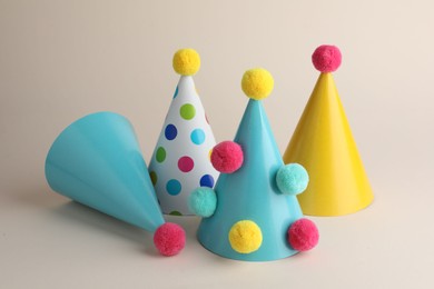 Colorful party hats with pompoms on beige background