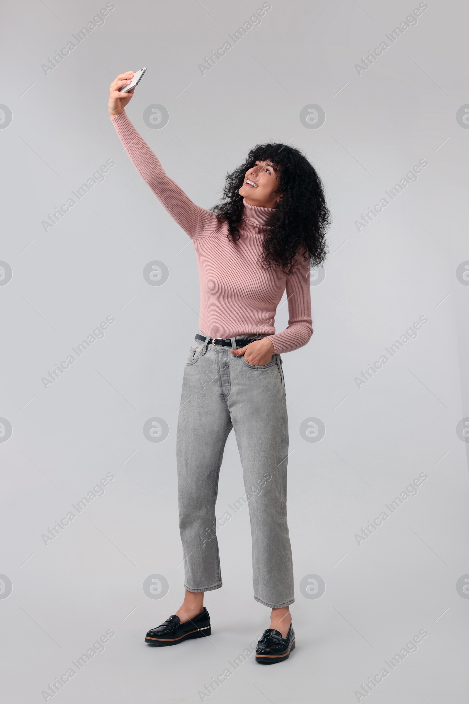 Photo of Beautiful young woman taking selfie on light grey background