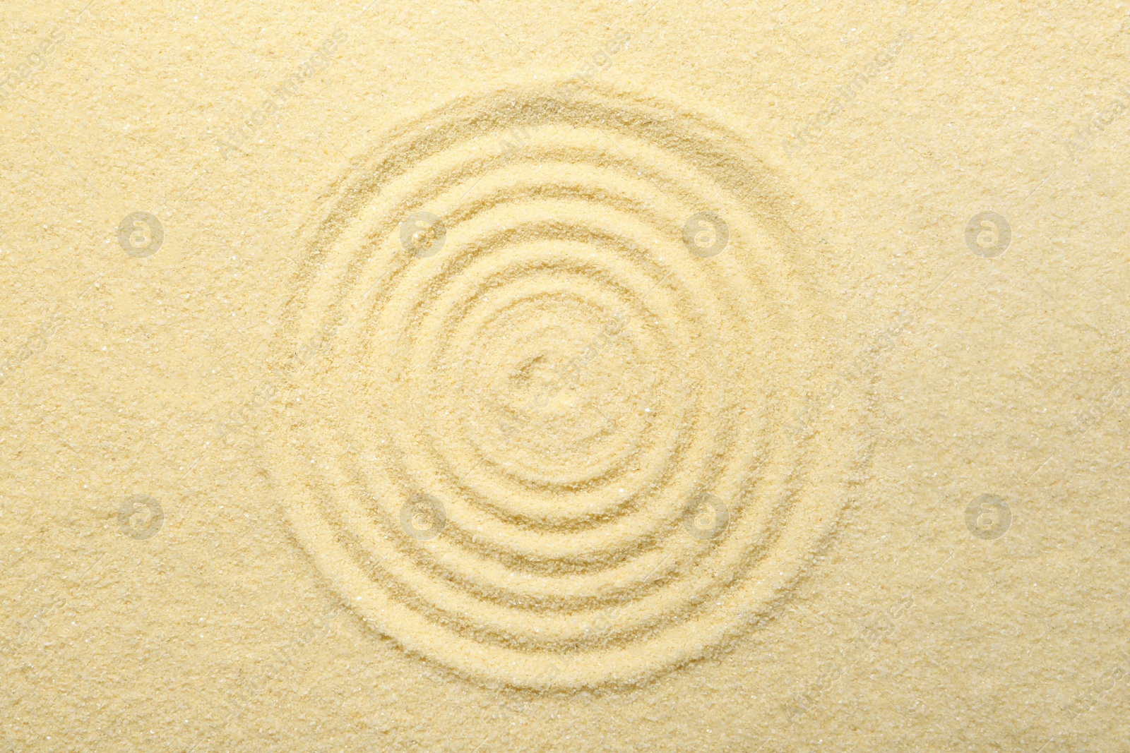 Photo of Zen rock garden. Circle pattern on beige sand, top view