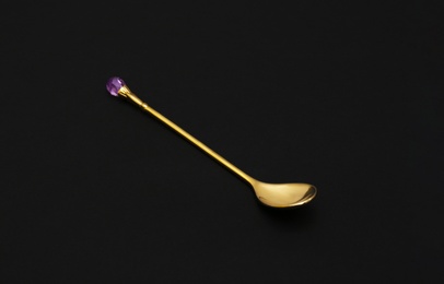 Shiny luxury gold spoon on black background