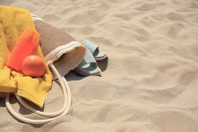 Photo of Beach bag, sunscreen and other accessories on sand. Space for text