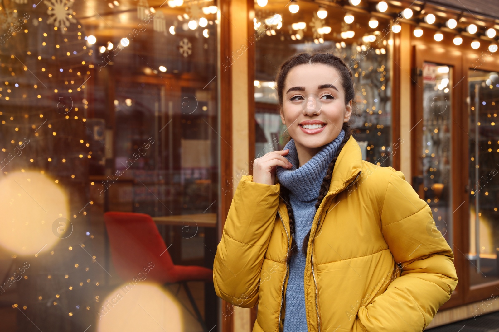 Photo of Young woman near cafe decorated for Christmas