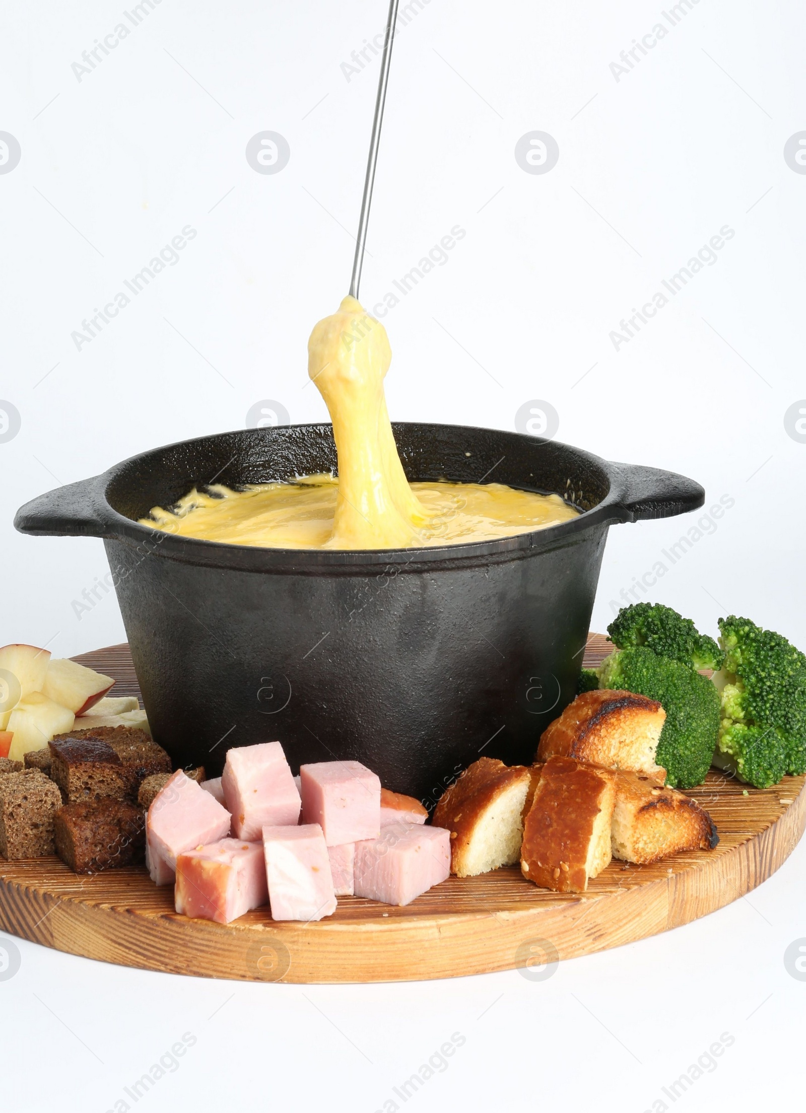 Photo of Dipping piece of ham into fondue pot with tasty melted cheese isolated on white