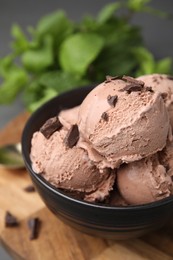 Photo of Bowl with tasty chocolate ice cream on wooden board, closeup