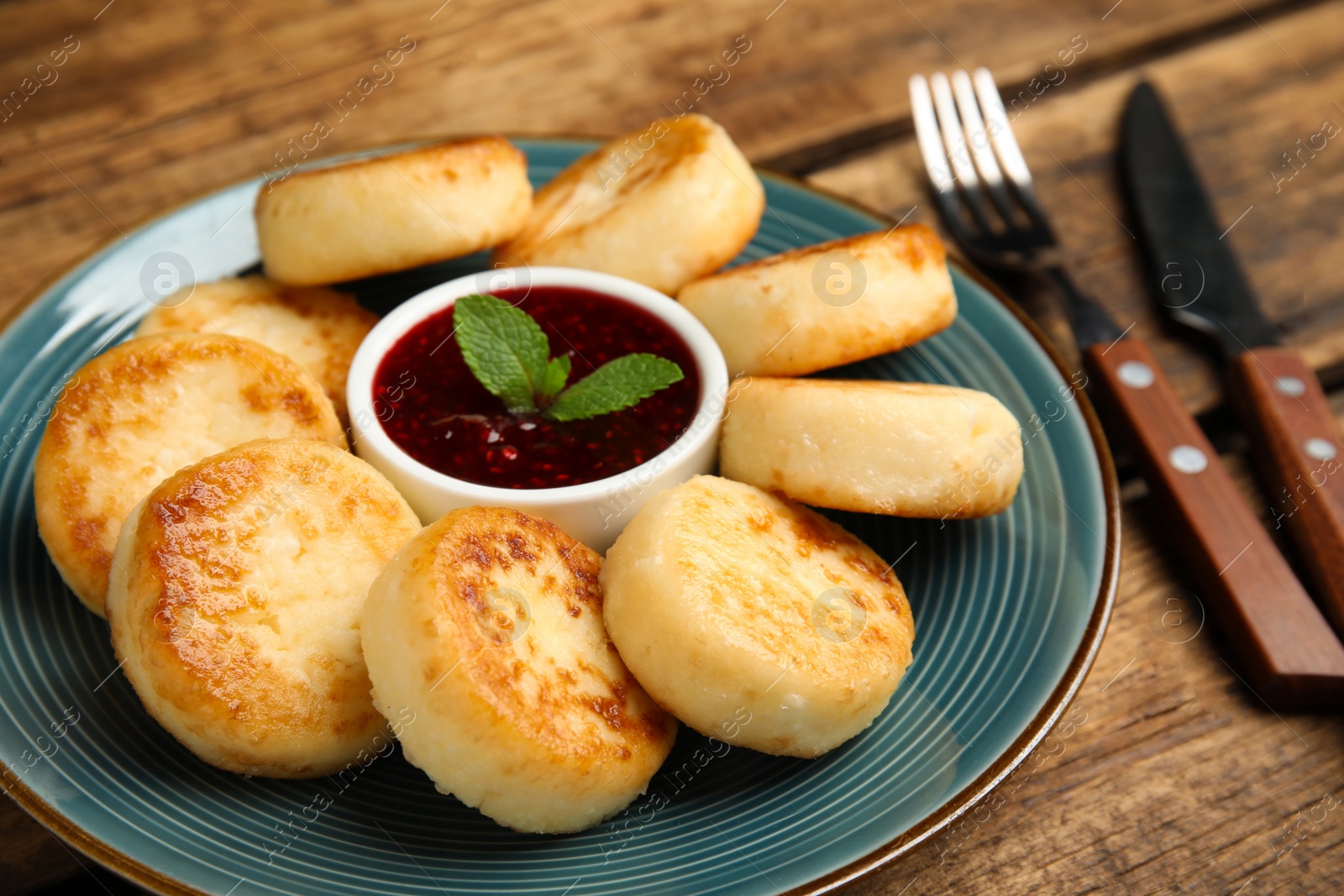 Photo of Delicious cottage cheese pancakes with jam and mint on wooden table