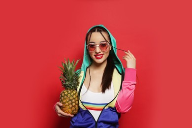 Young woman with fresh pineapple on red background. Exotic fruit